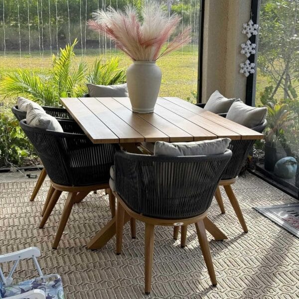 Elegant Purple Leaf Patio Dining Set with a wooden table and comfortable black rope chairs, placed in a cozy outdoor space with lush greenery in the background.